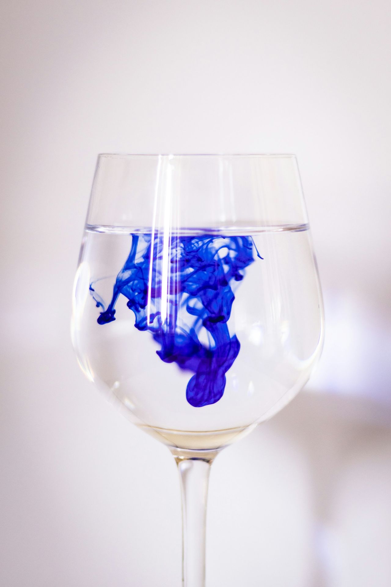Blue and white liquids in a wine glass.